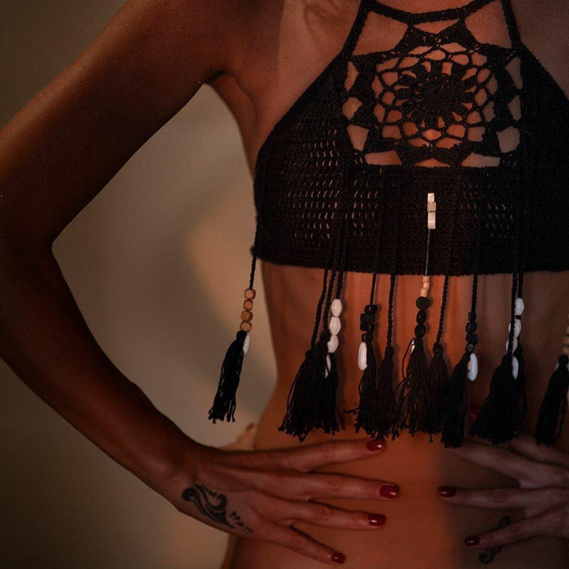 Black crochet top with tassels and beads on a neutral background