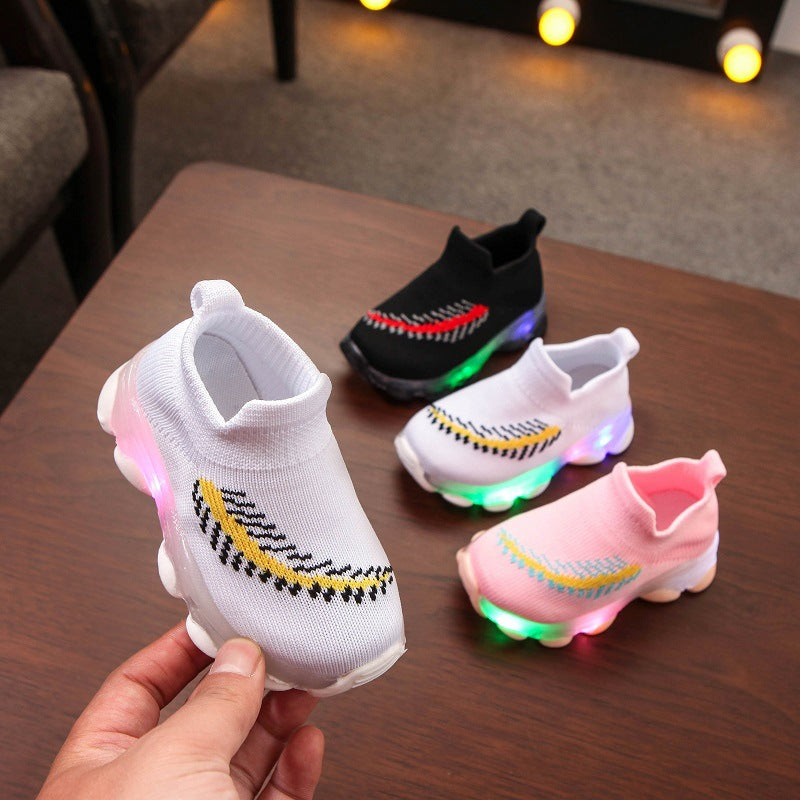 Colorful children's LED shoes on a wooden surface with a blurred background.