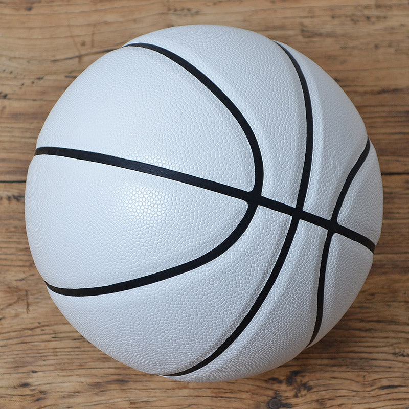 White basketball with black lines on a wooden surface