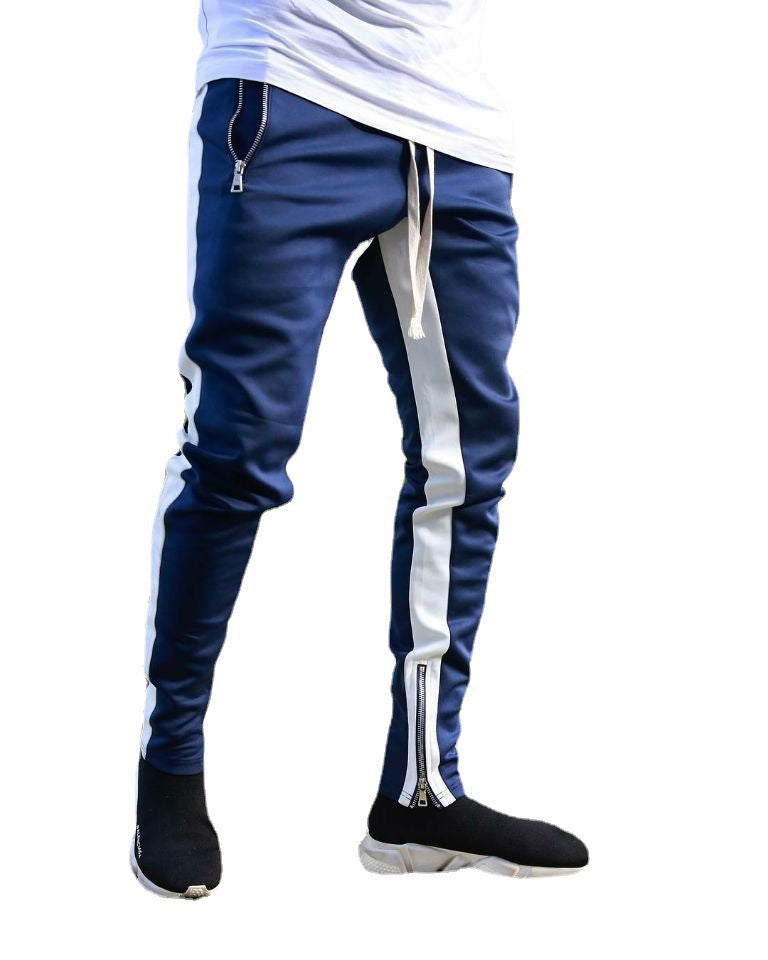 Blue jogger pants with white stripes and zippers on a white background