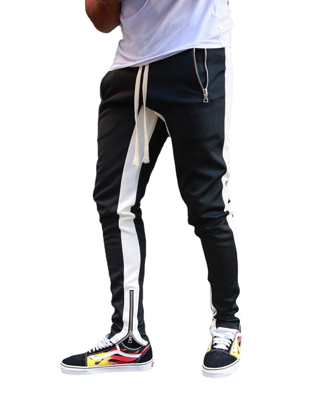 Black and white track pants with side stripes worn by a person on a white background