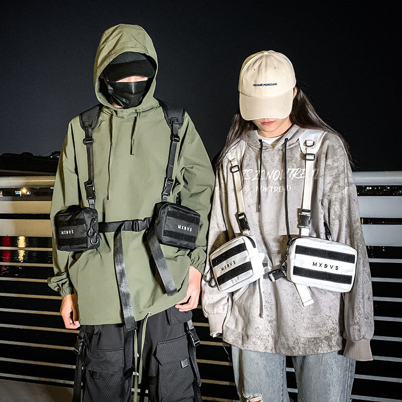 Two people wearing tactical outfits with bags and gear on a dark background