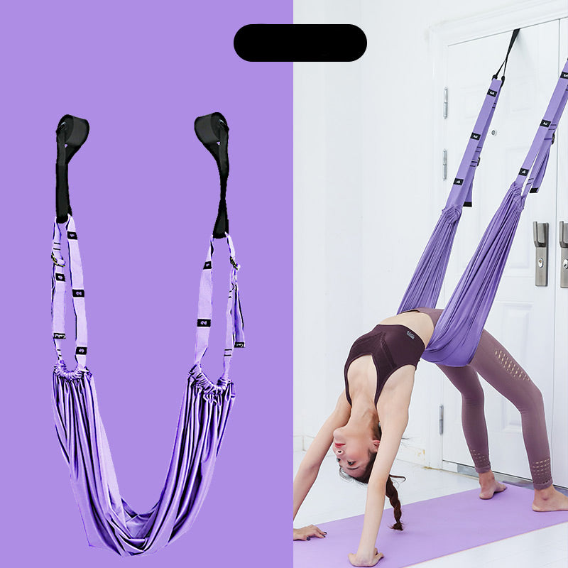 Purple aerial yoga hammock with a person practicing yoga on a purple mat.