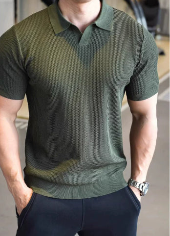 Man wearing a green textured polo shirt and dark pants indoors.