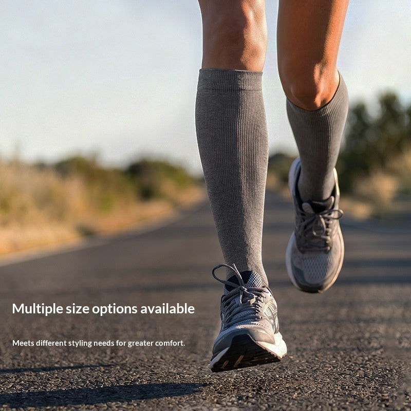 A person running outdoors wearing gray knee-high compression socks and gray running shoes on a paved road, with the text 'Multiple size options available' overlaid at the bottom left.