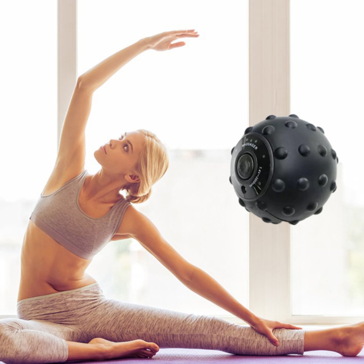 Woman stretching with a black massage ball in a bright room