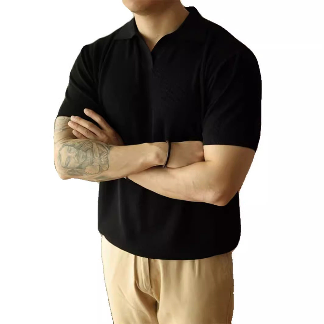 Person wearing a black polo shirt and beige pants with arms crossed on a white background