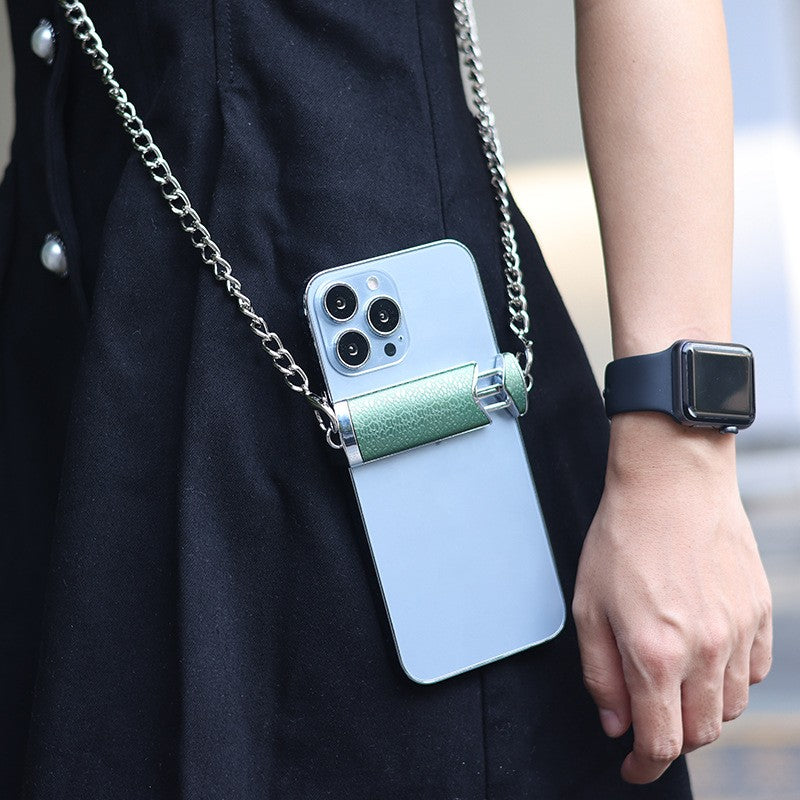 Person holding a phone with a reflective case and chain strap, wearing a black coat.