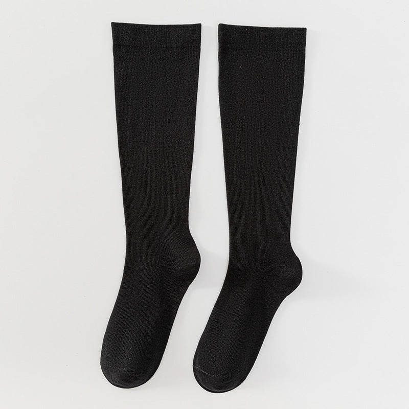 Pair of black knee-high socks on a light gray background