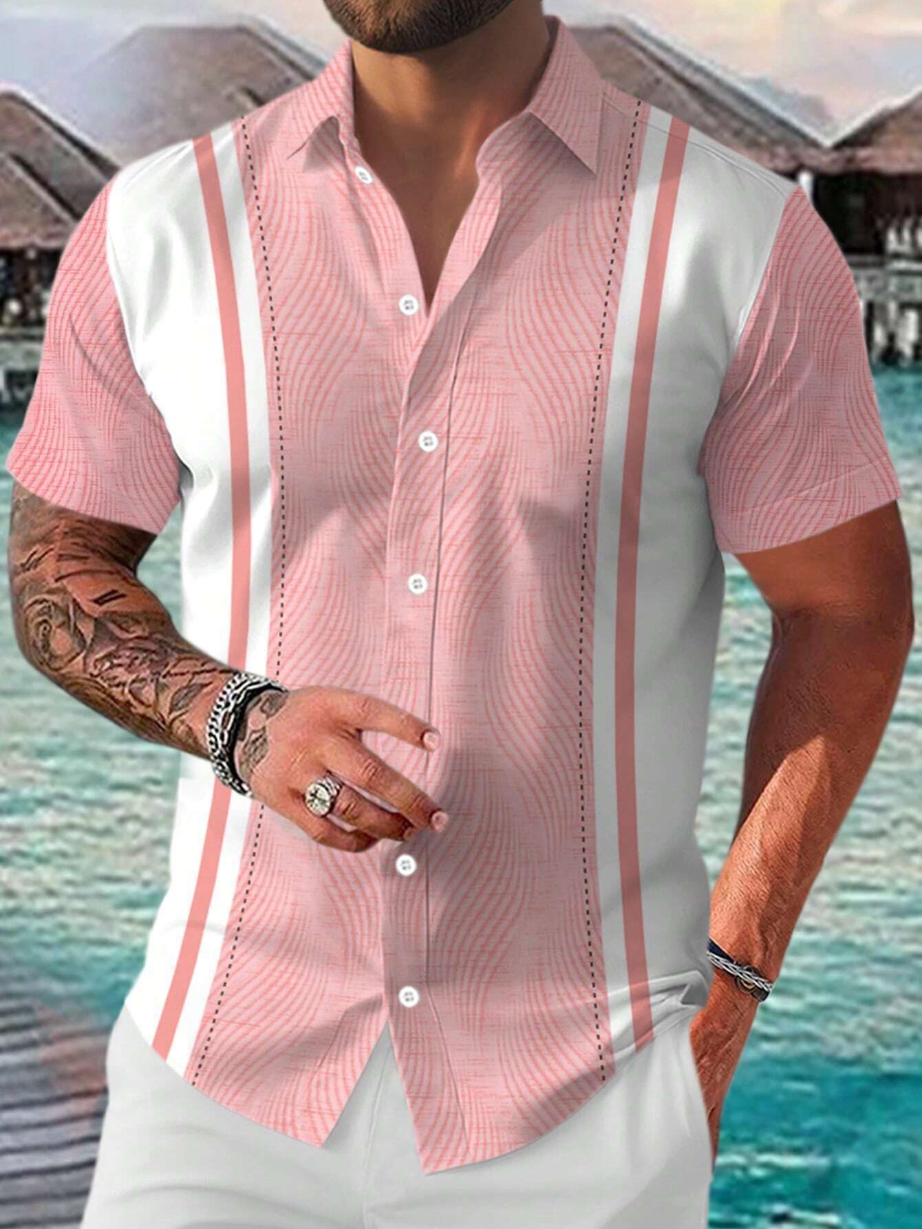 Man wearing a pink and white patterned shirt with a blurred background of water and structures.