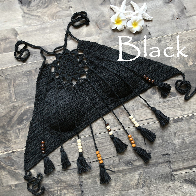 Black crochet bag with tassels and beads on a wooden surface