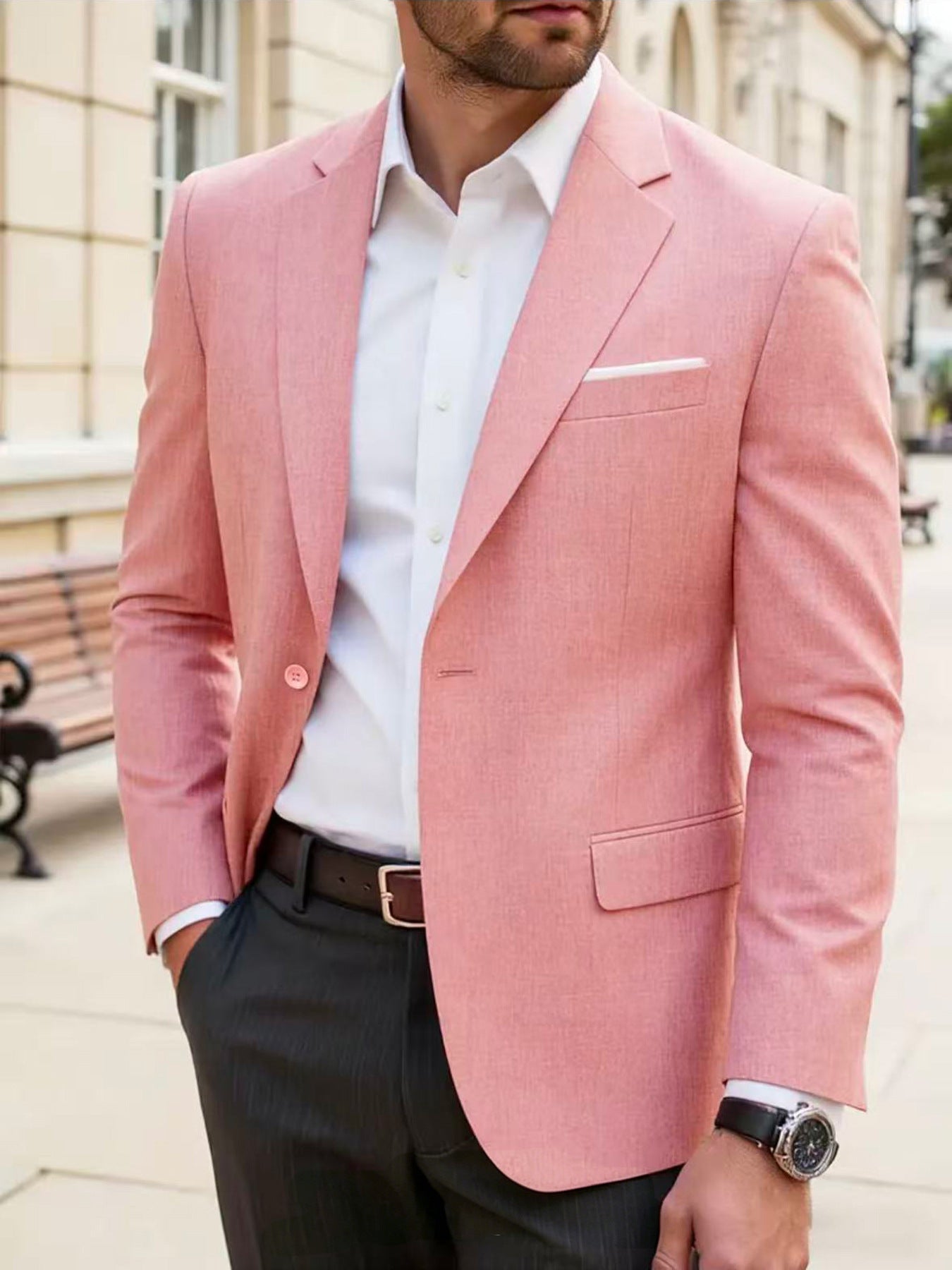 Man wearing a pink blazer over a white shirt with black pants outdoors.