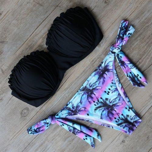 Black bikini top and colorful palm tree patterned bottom on a wooden surface