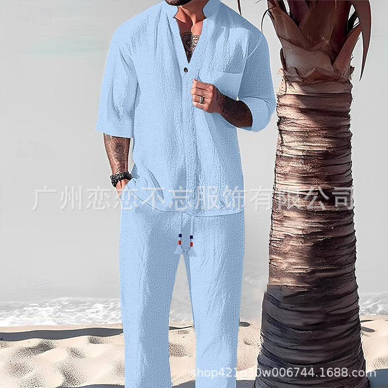 Person wearing a light blue outfit standing next to a palm tree on a beach.