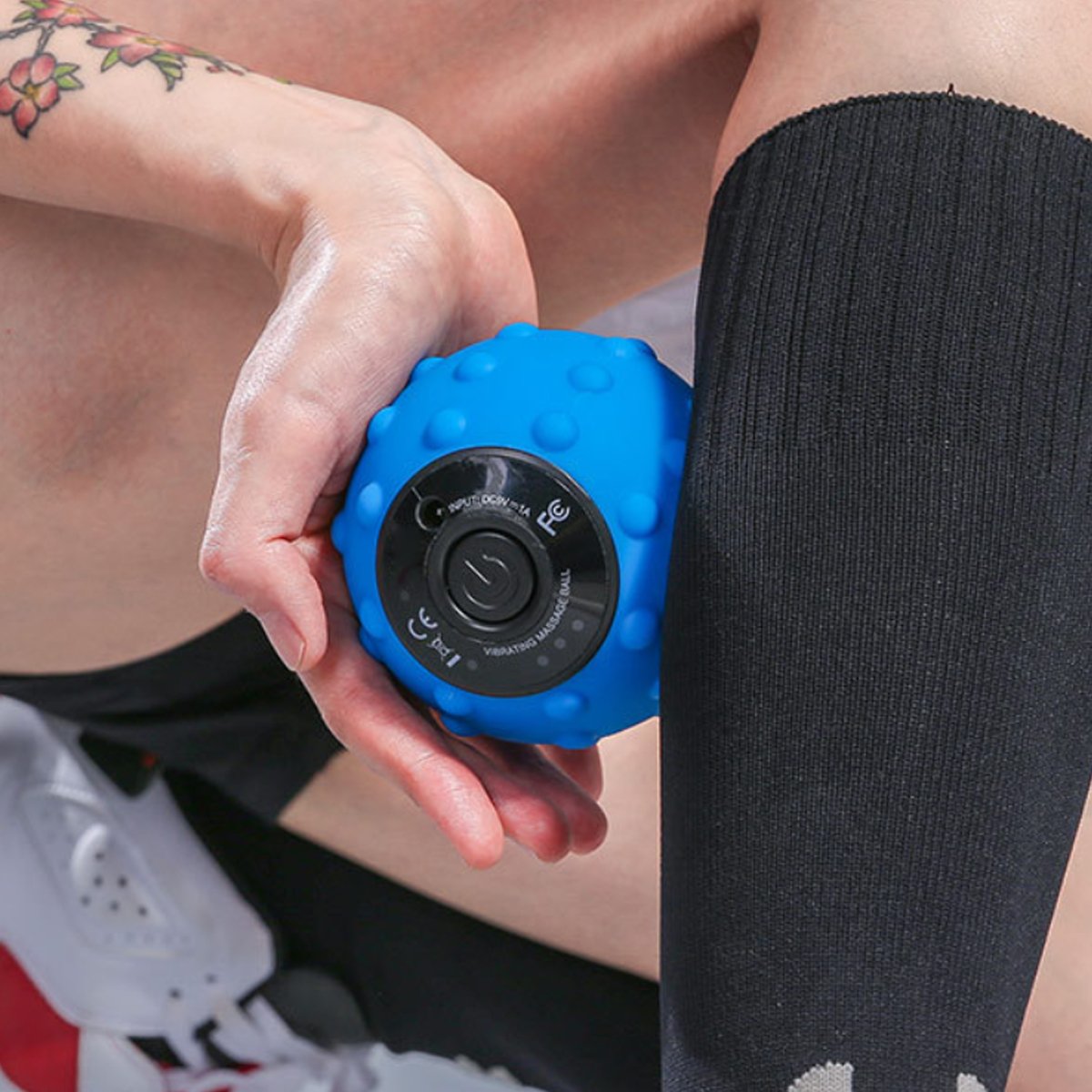 Person holding a blue handheld massager against their leg