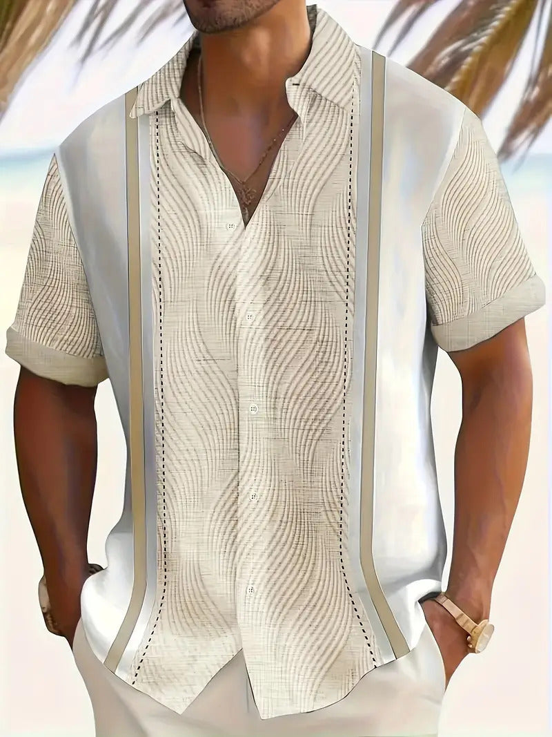 Man wearing a white patterned shirt with a blurred beach background