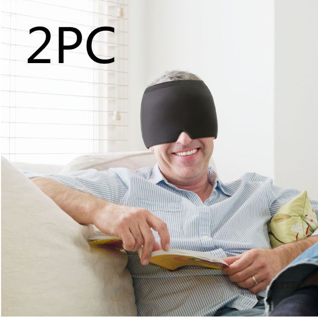 Man wearing a black sleep mask while reading a book on a couch.