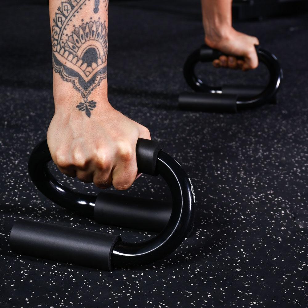 Person using black exercise rings on a dark surface