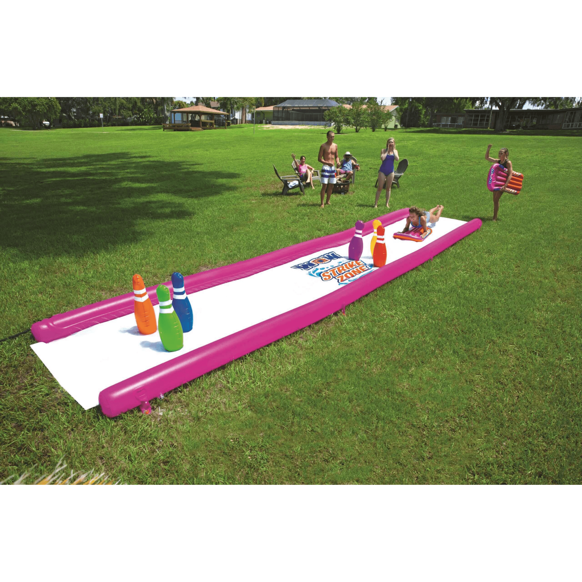 Inflatable water slide with bowling pins on a grassy field, people in the background.