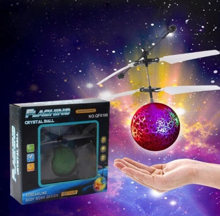 Colorful flying ball toy with packaging and a hand holding it against a space-themed background