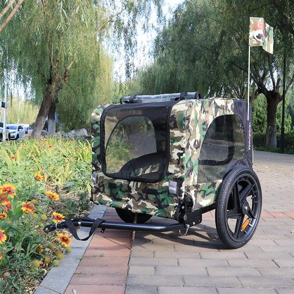 Camouflage-patterned pet bike trailer on a sidewalk with trees and flowers in the background