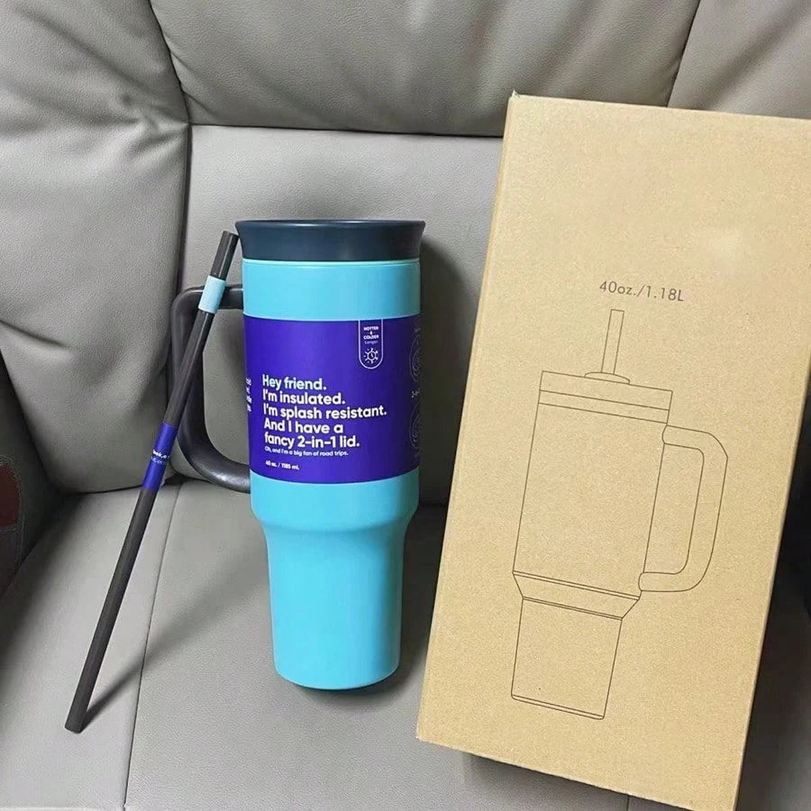 Turquoise 40 oz travel tumbler with dark handle and lid, straw alongside, beside a cardboard product box.