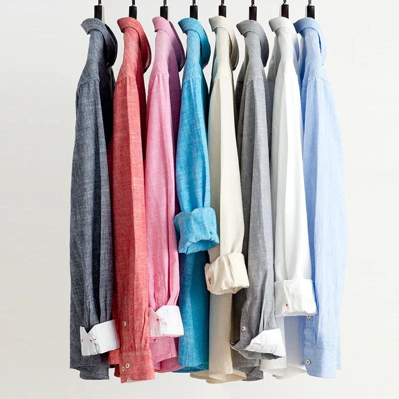 Row of colorful shirts hanging on a rack against a white background