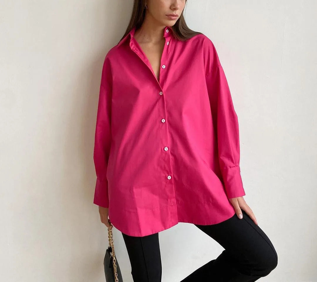 Person wearing a bright pink shirt and black pants against a plain background