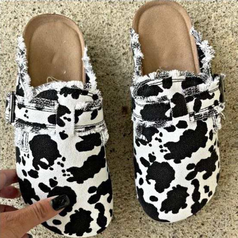 Pair of cow print sandals on a textured surface