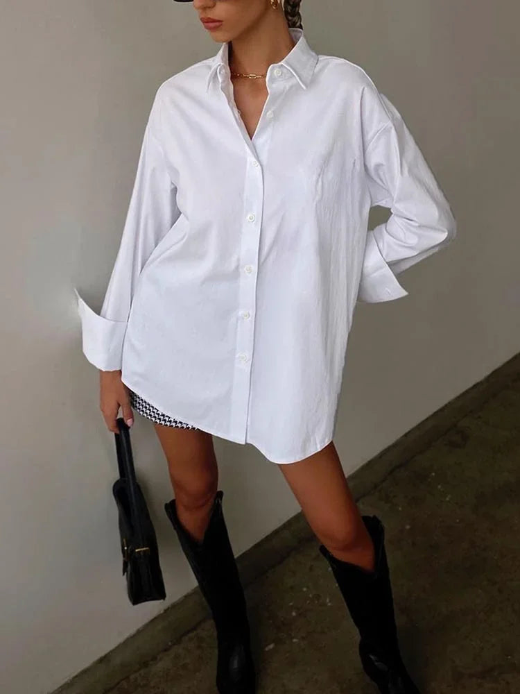 Person wearing an oversized white shirt with knee-high black boots against a neutral background