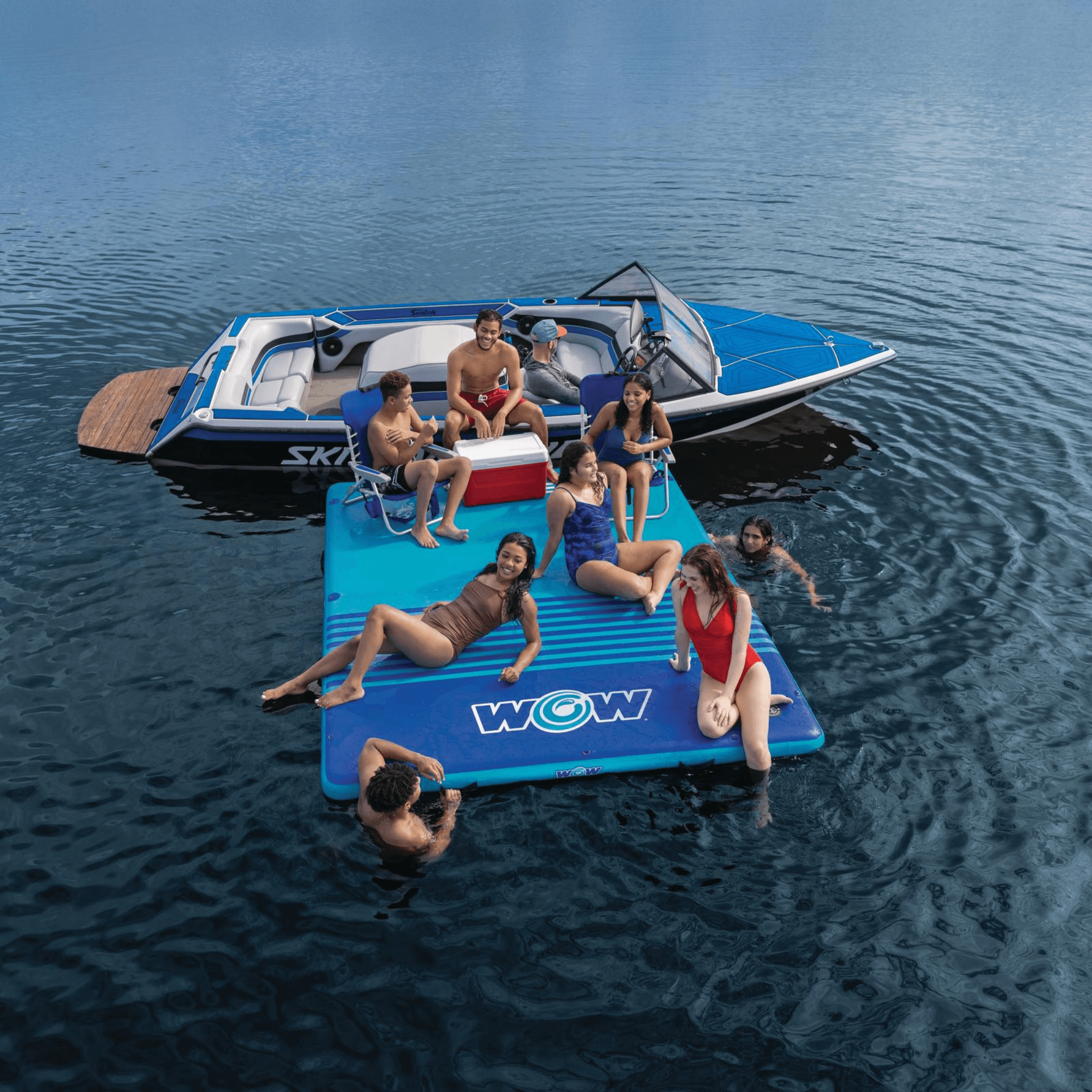 People enjoying a day on a blue inflatable platform with 'WOW' branding in the water.