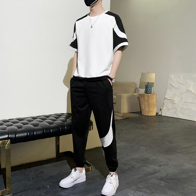 Person wearing a black and white outfit with a modern interior background