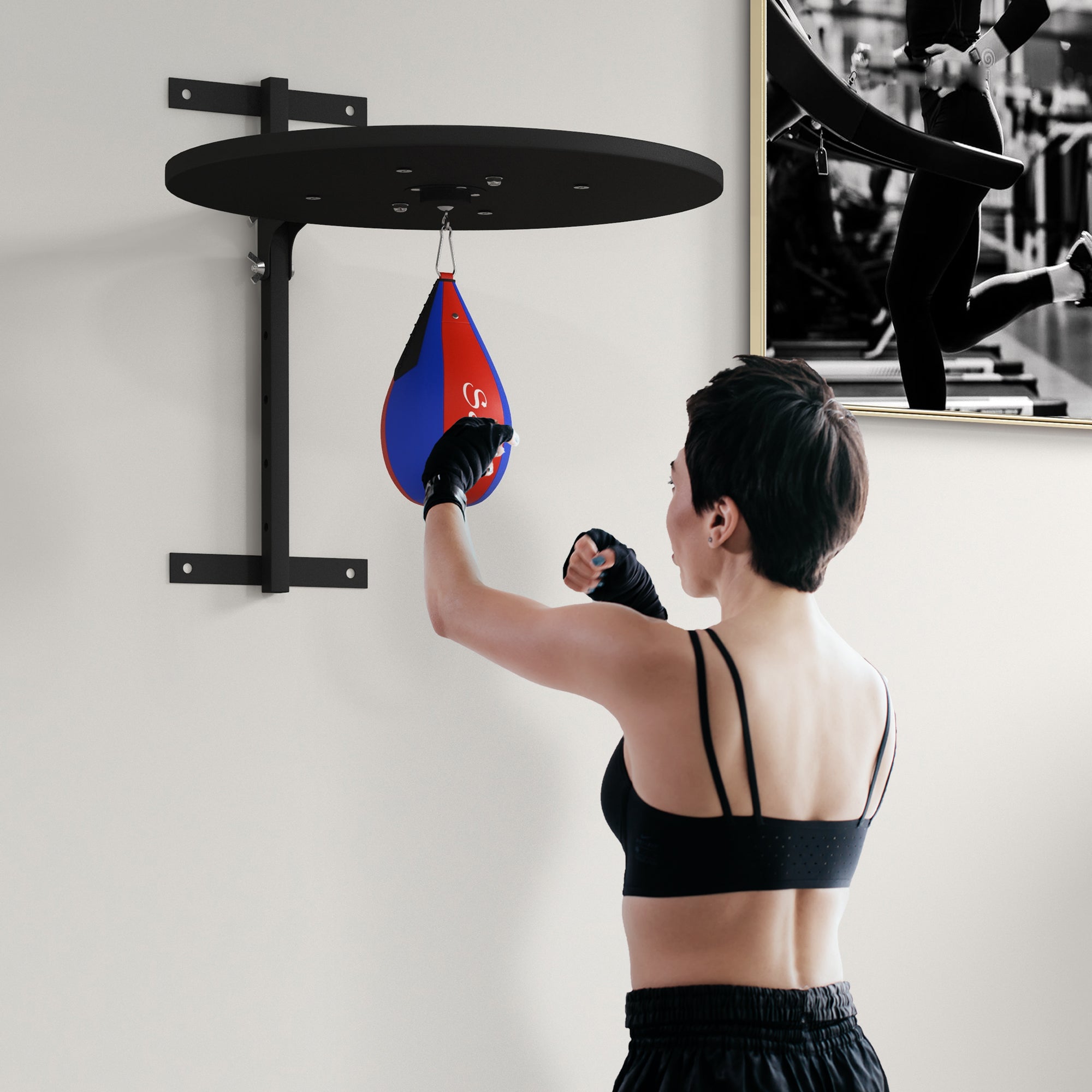 Person using a punching bag attached to a wall mount in a home gym setting.