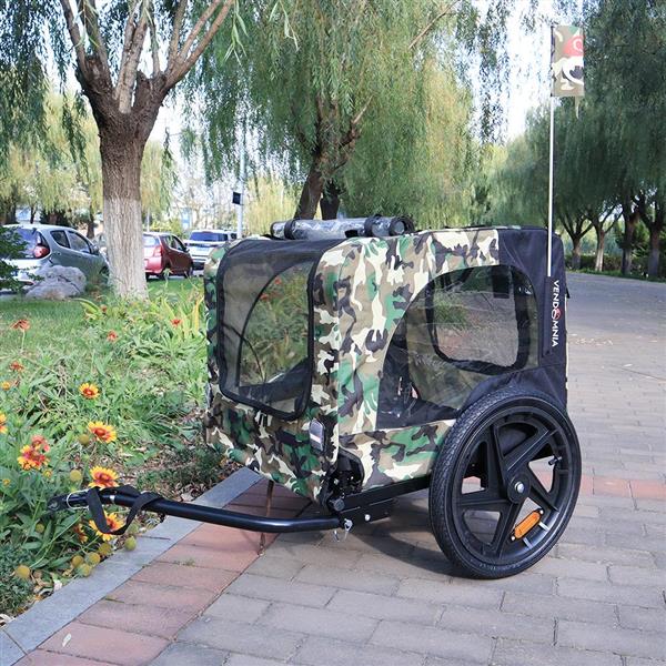 Camouflage-patterned pet stroller on a sidewalk with trees and flowers in the background