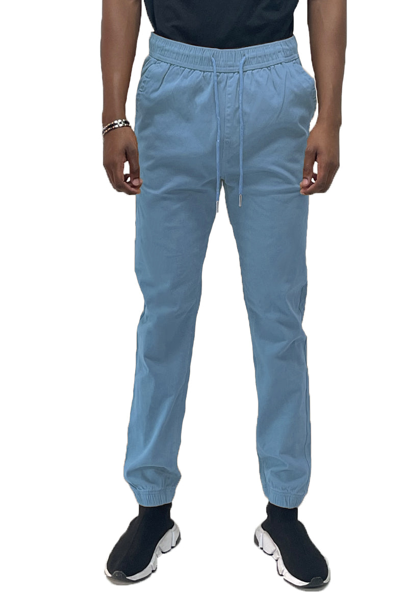 Person wearing light blue jogger pants on a white background