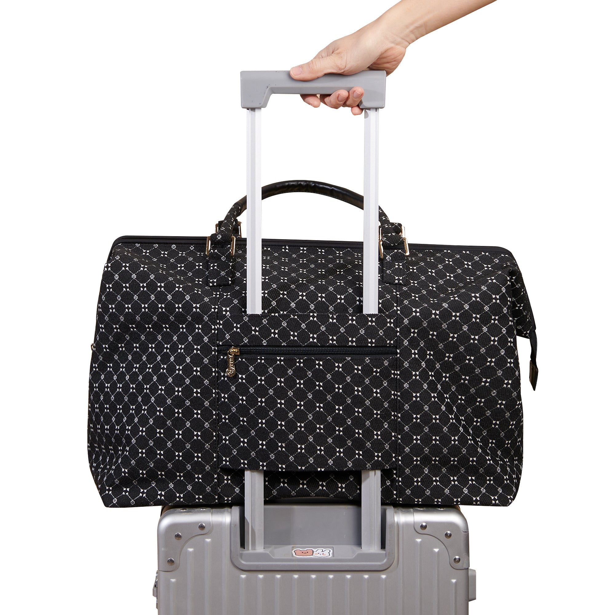 Black patterned suitcase with a hand holding onto the handle against a white background