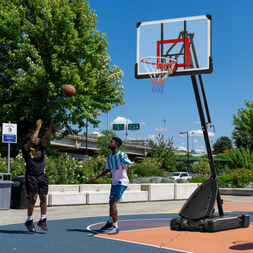 Two people playing basketball on an outdoor court with a clear blue sky.
