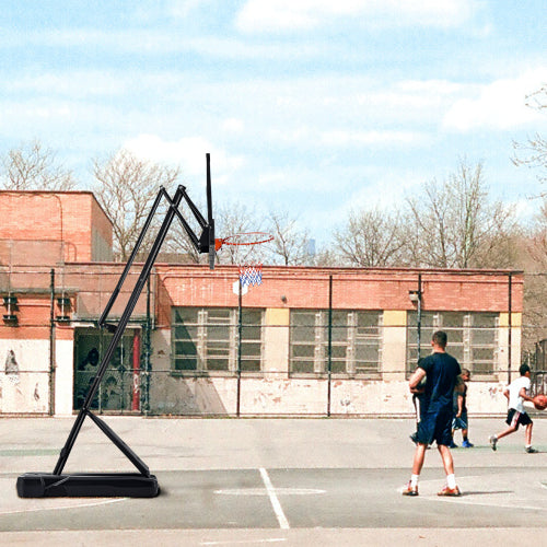 Basketball game on an outdoor court with a building in the background