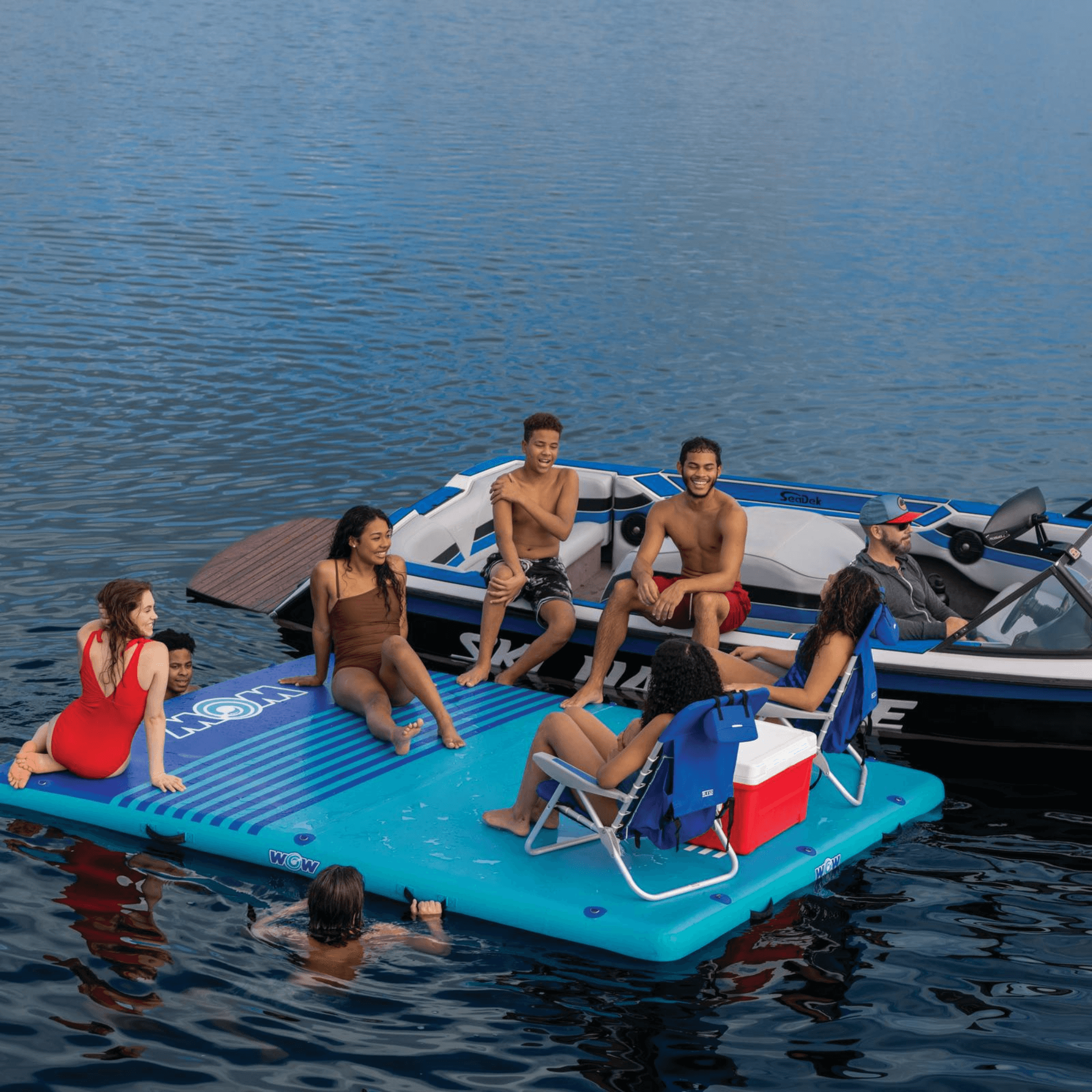 Group of people on an inflatable platform in the water with a boat in the background.