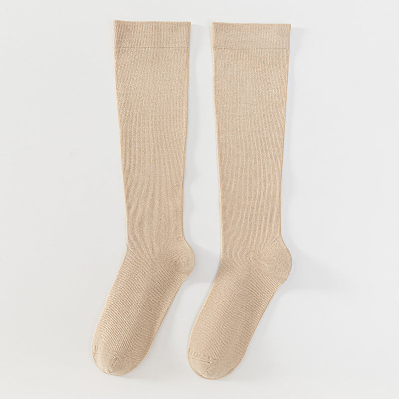 A pair of ribbed knee-high socks in a light beige color, displayed flat against a clean white background.