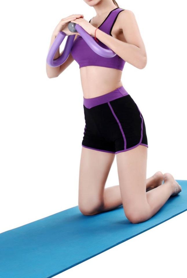 Person in purple sports bra and black shorts using a muscle strength on a blue mat.