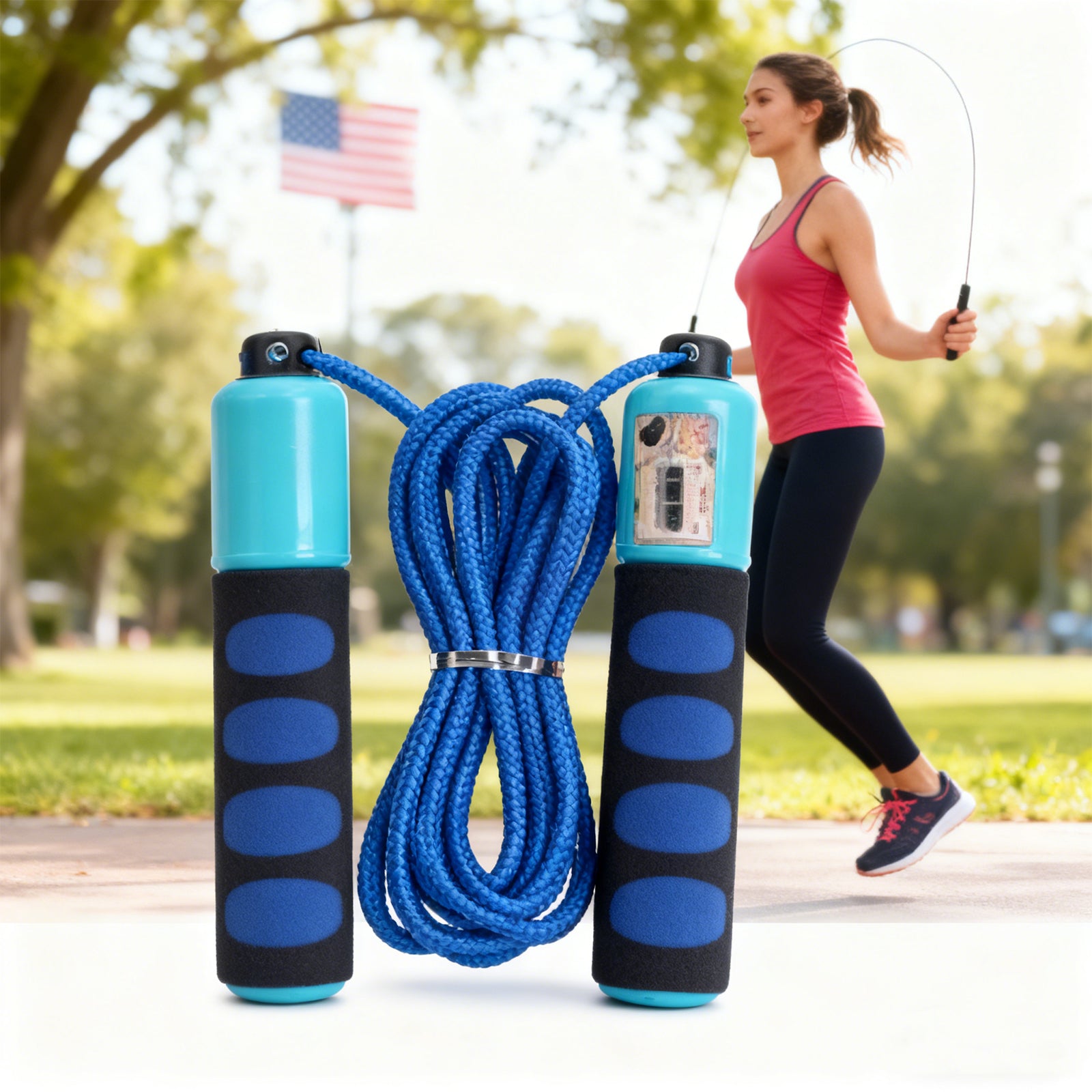Blue jump rope with black handles in front of a woman skipping in a park.
