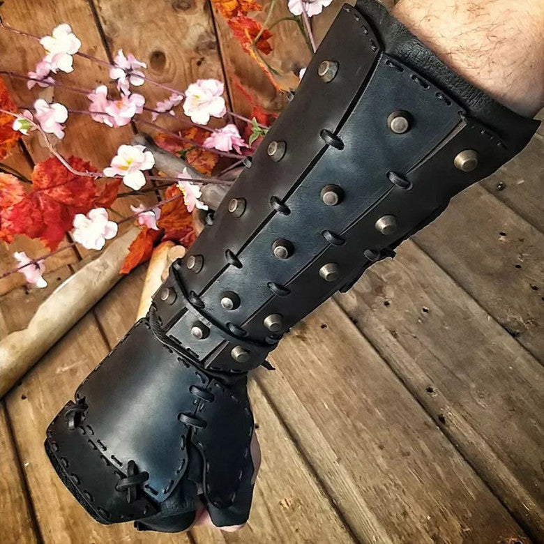 Black leather boxing glove with metal studs on a wooden surface with flowers.