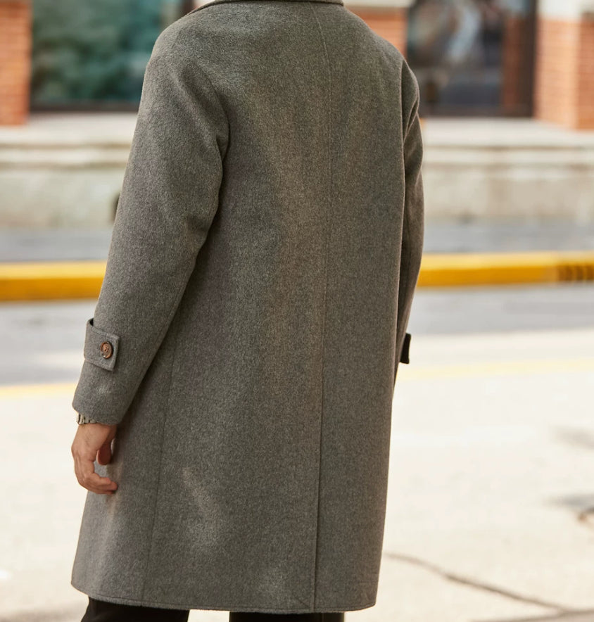 A person viewed from behind wearing a mid-length gray wool coat outdoors on a city street.