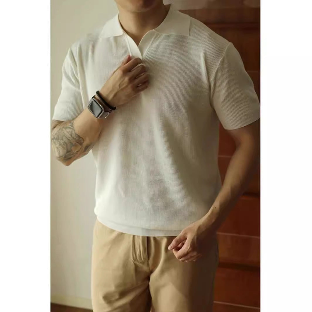 Person wearing a white polo shirt and beige pants with a neutral background
