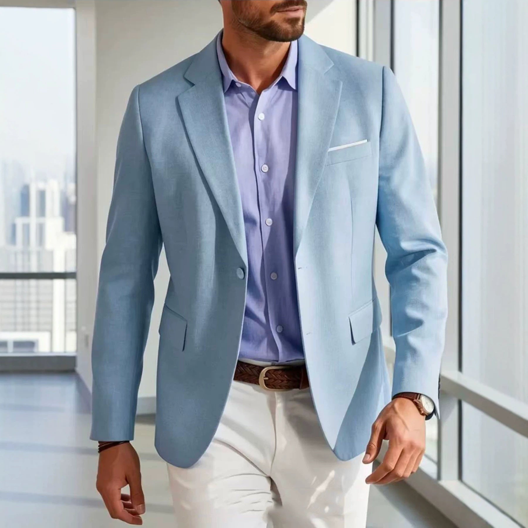 Man wearing a light blue blazer over a purple shirt with white pants in an indoor setting.