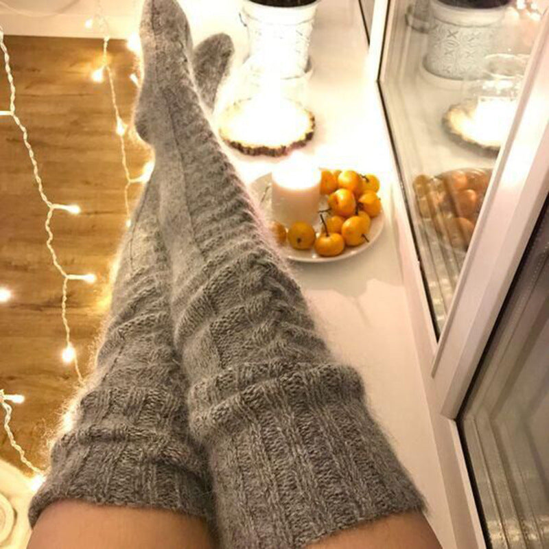 Person wearing gray socks in a kitchen with a plate of oranges on the counter.