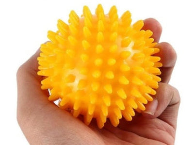 Yellow spiky ball held in a hand against a white background