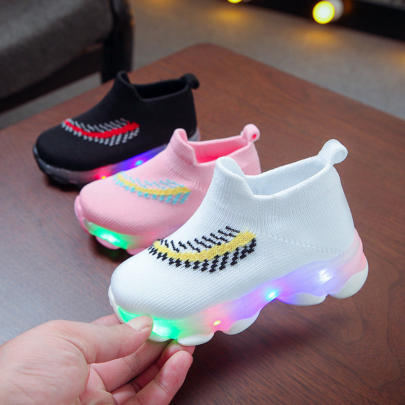 Colorful LED children's shoes on a wooden surface with blurred background