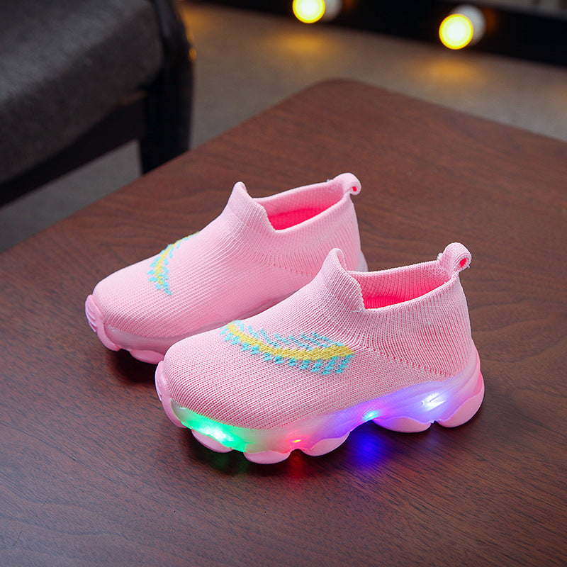 Pink children's shoes with LED lights on a wooden surface